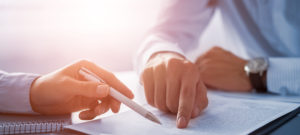 Business people negotiating a contract. Human hands working with documents at desk and signing contract.