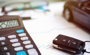 calculator next to car keys and car on paper