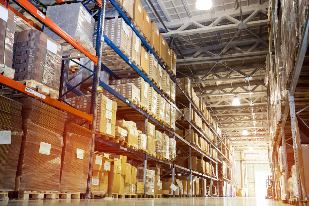 A modern warehouse interior with shelves stacked high with pallets loaded with product.